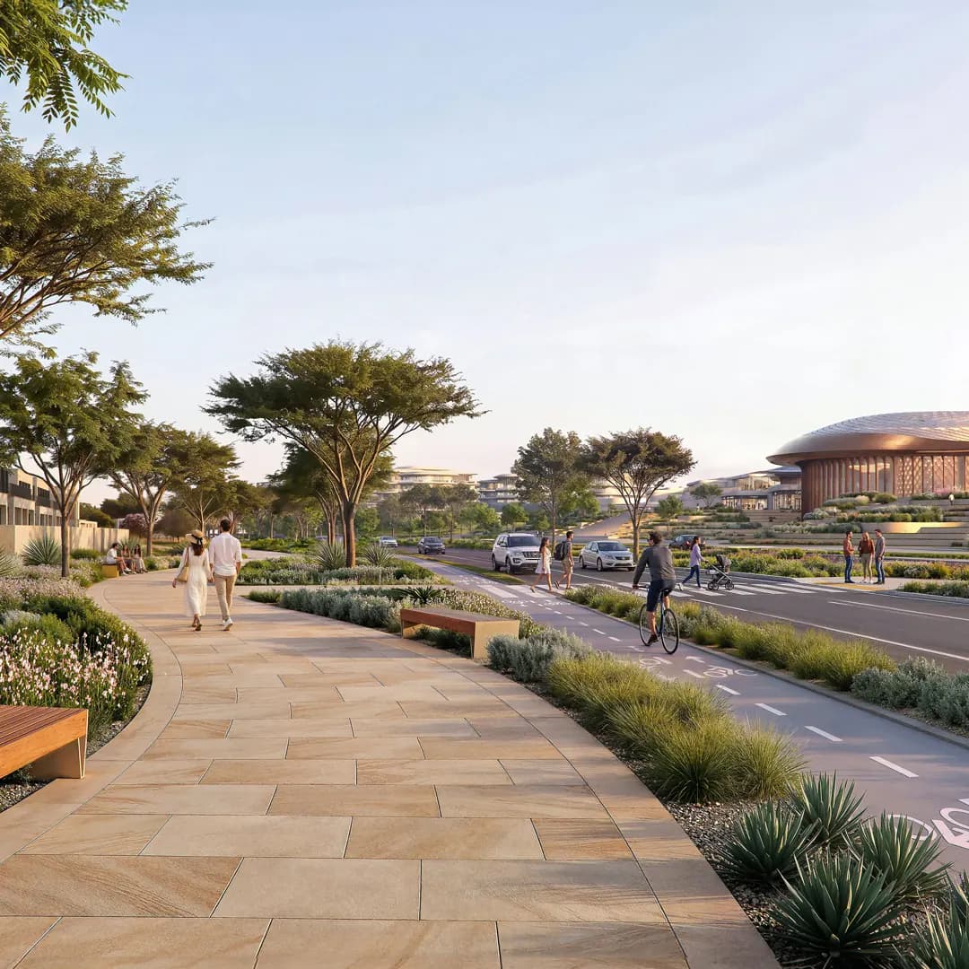 Tree-lined paved walkway beside a cycle lane leading towards the arena
